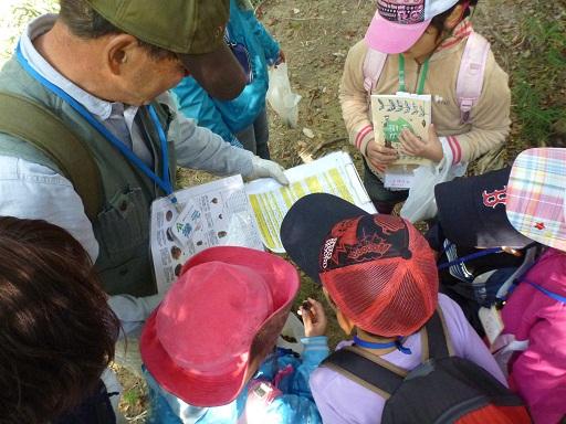 男性の持った資料を子供たちがのぞき込んで見ている写真